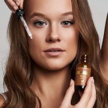 Kobieta aplikująca serum Sattva Ayurveda na twarz przy pomocy pipety - odżywcze esencje pełne naturalnych składników dla promiennej skóry
