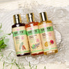 Naturalne szampony trychologiczne do różnych typów włosów Sattva Ayurveda – Shikakai, Honey Almond i Mango, ustawione w wodzie z zielonymi roślinami, prezentujące ajurwedyjską pielęgnację skóry głowy i włosów.